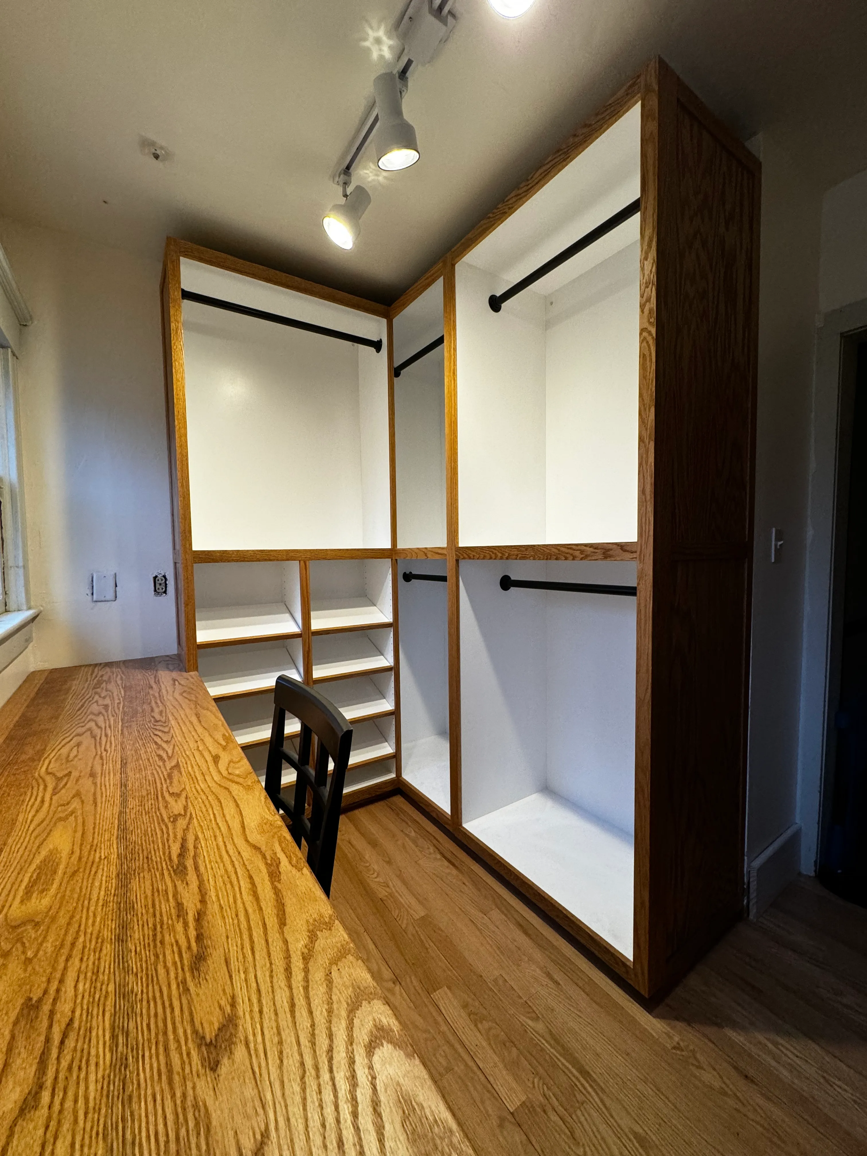 Fitted walk-in closet with red oak face frames, white interiors, double-hung blackened steel rods, and a solid oak countertop.