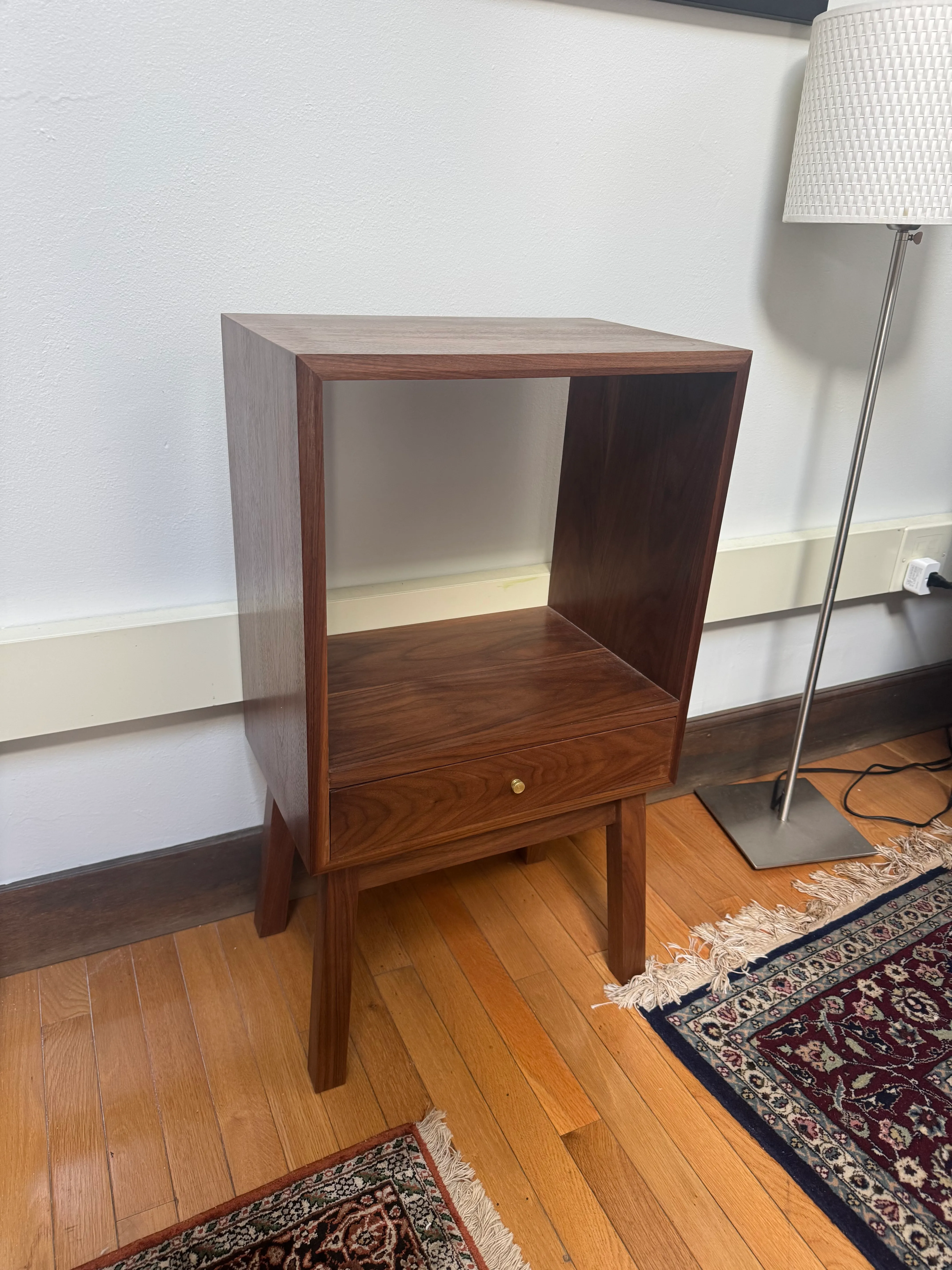 Solid walnut side table with an open upper cubby and a single lower drawer with a small brass knob, on angled legs.