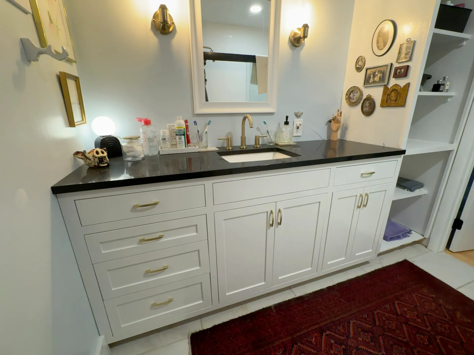 White painted vanity with a honed black stone top, brushed brass hardware, and an undermount sink, Champaign, Illinois.
