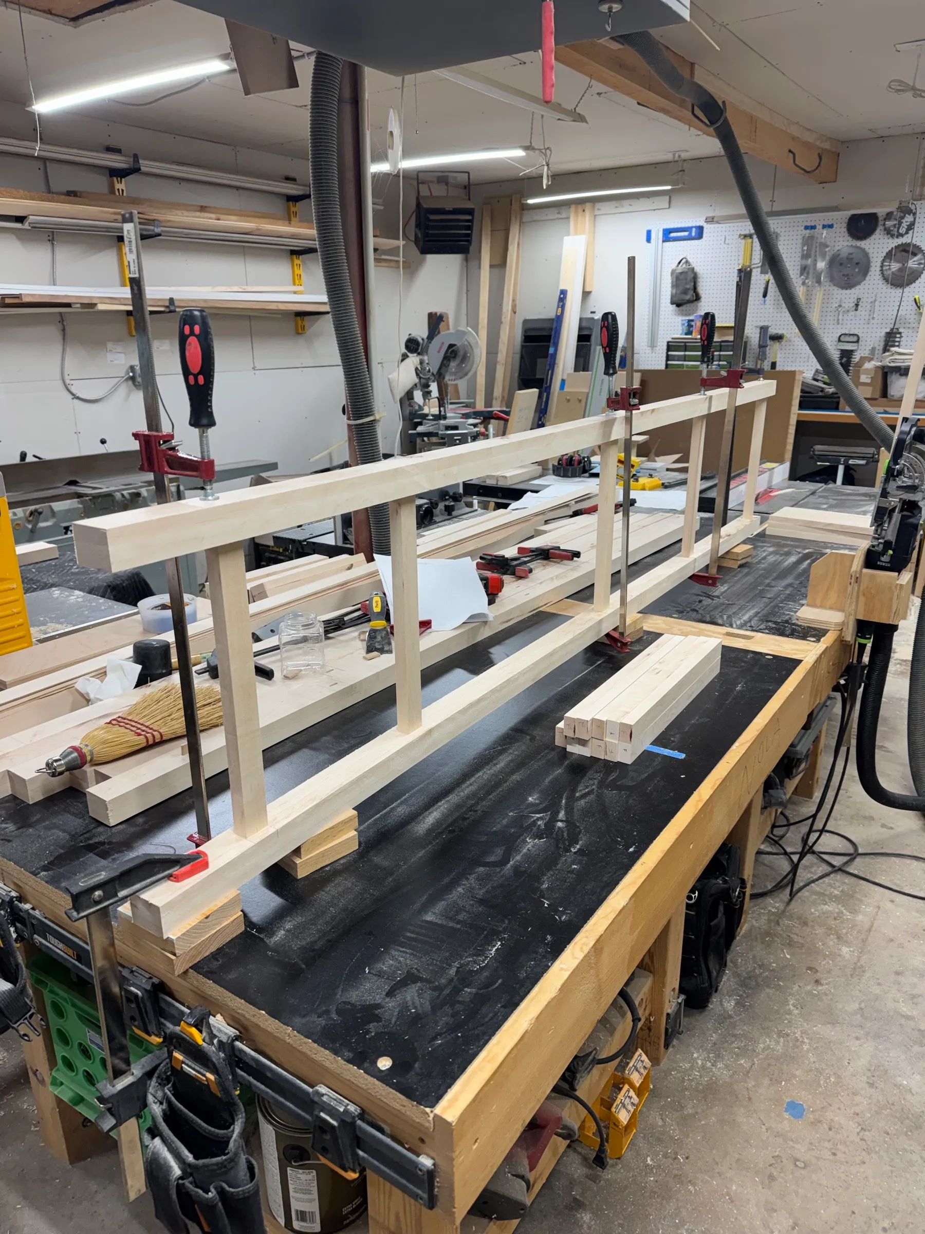 A maple frame ladder clamped up on the bench, posts and rails dry-fit to check the bay spacing.