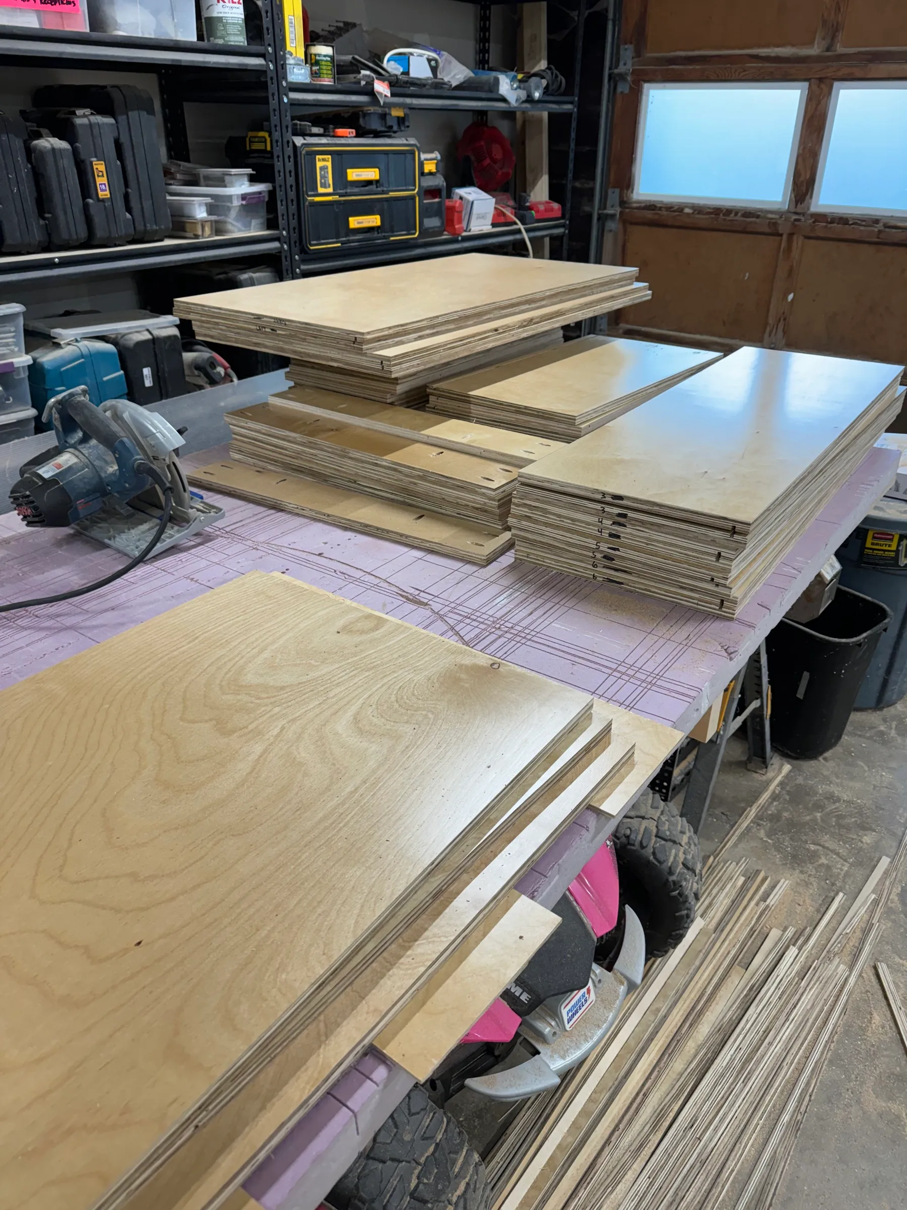 Sheets of birch plywood cut to size and stacked on a saw station in the shop.
