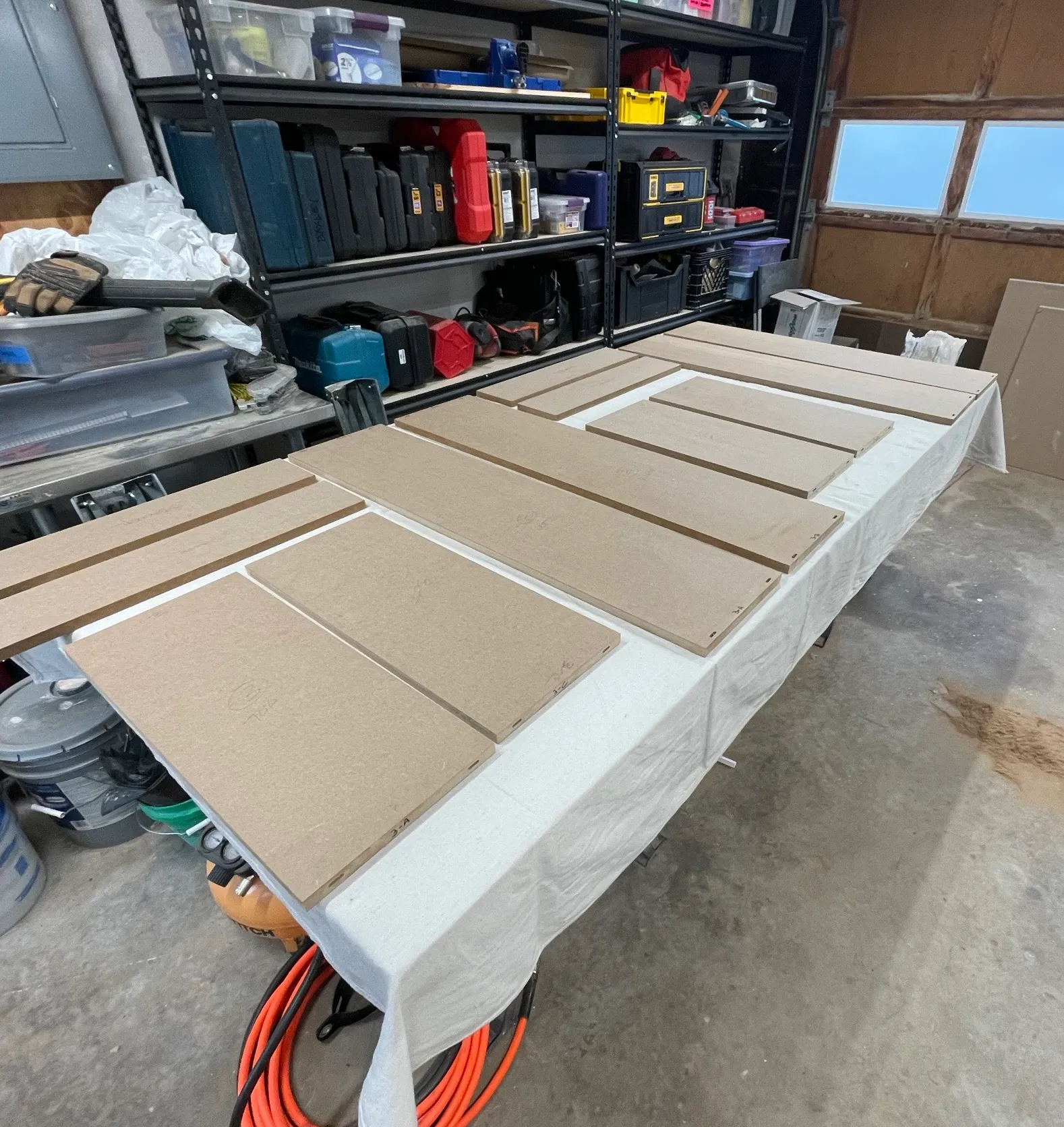 MDF panels laid out flat on a drop-cloth-covered bench in the shop, spaced apart and ready for primer.
