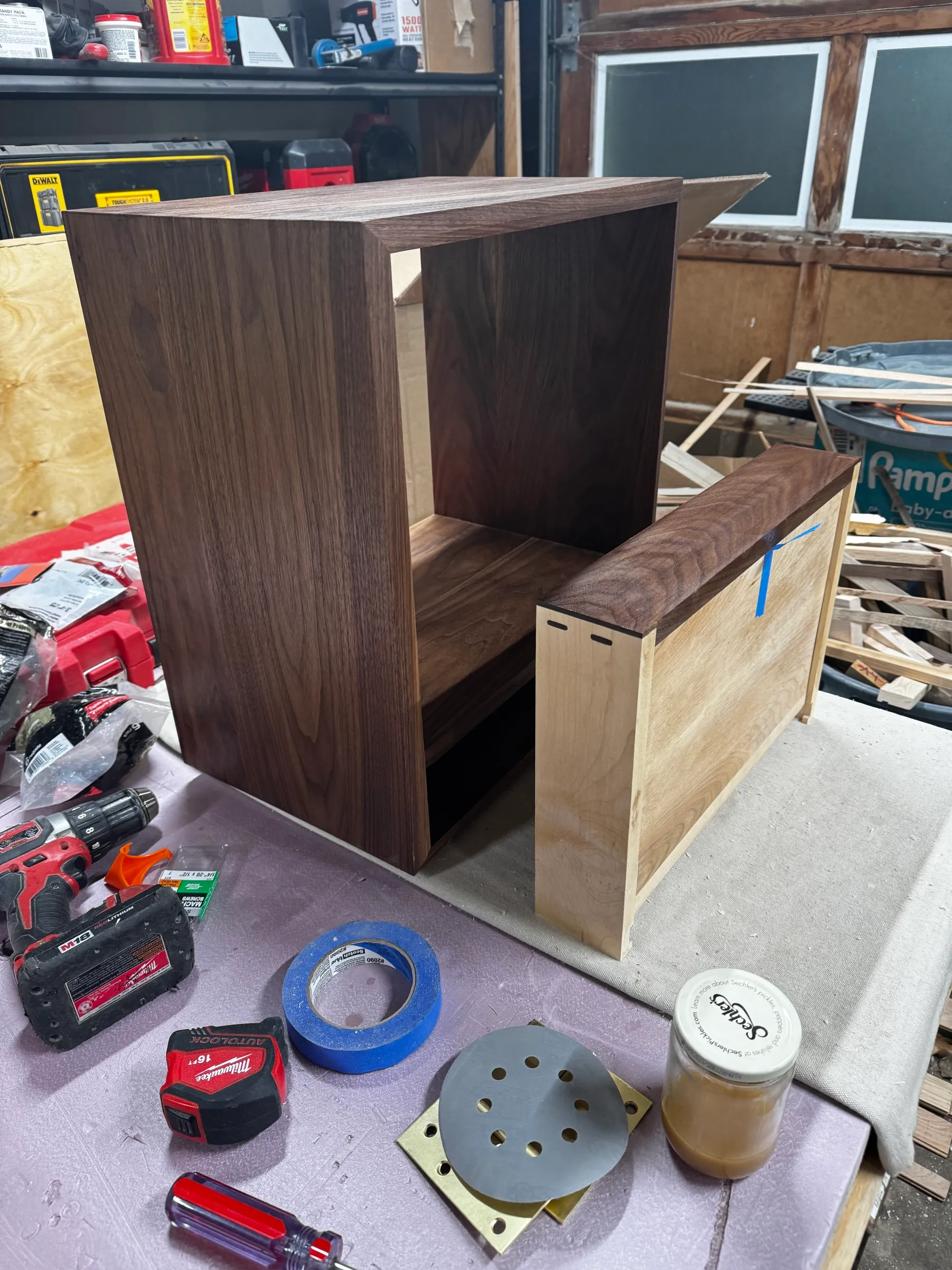 The walnut table box and its drawer box sitting apart on the bench, brass hardware and sandpaper nearby.