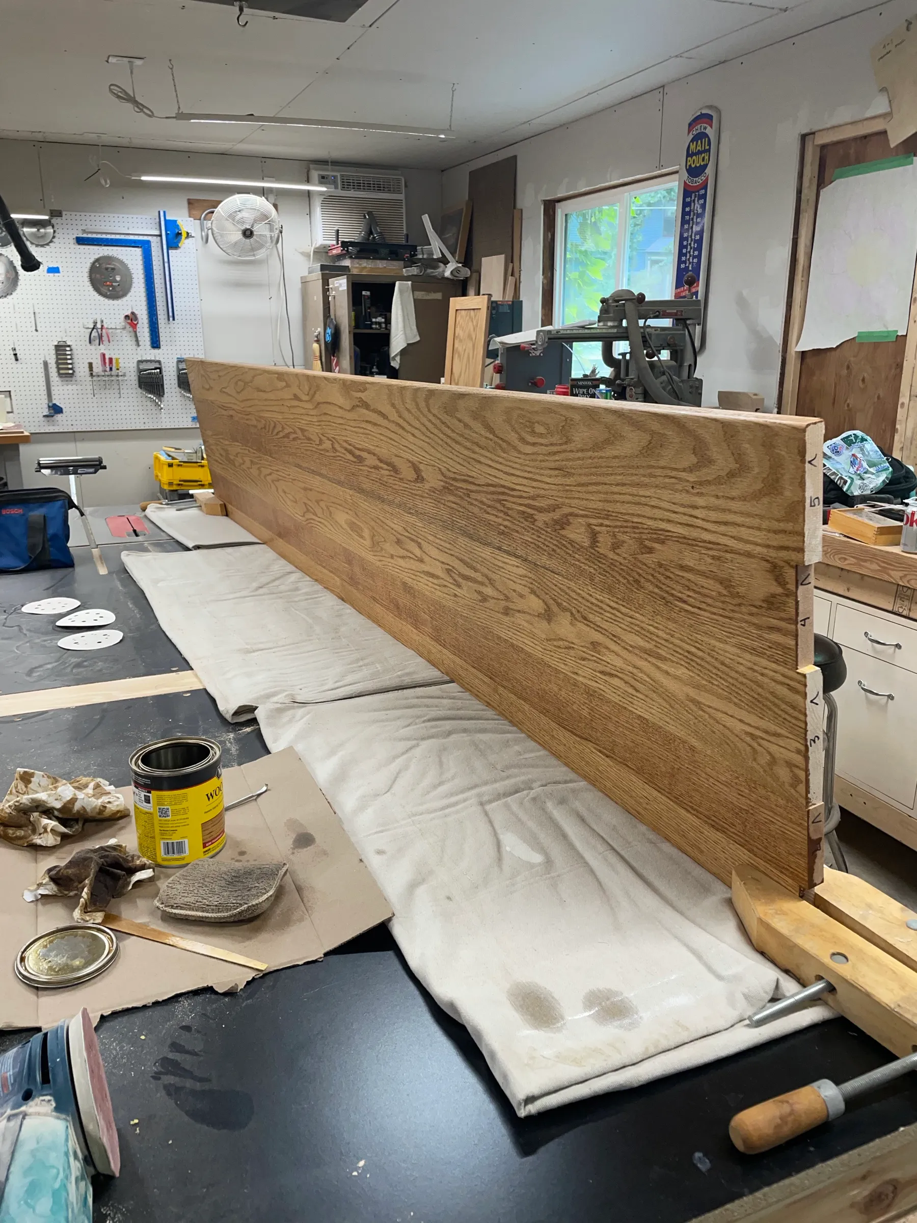 A large stained red oak countertop panel resting on a drop cloth after finishing.