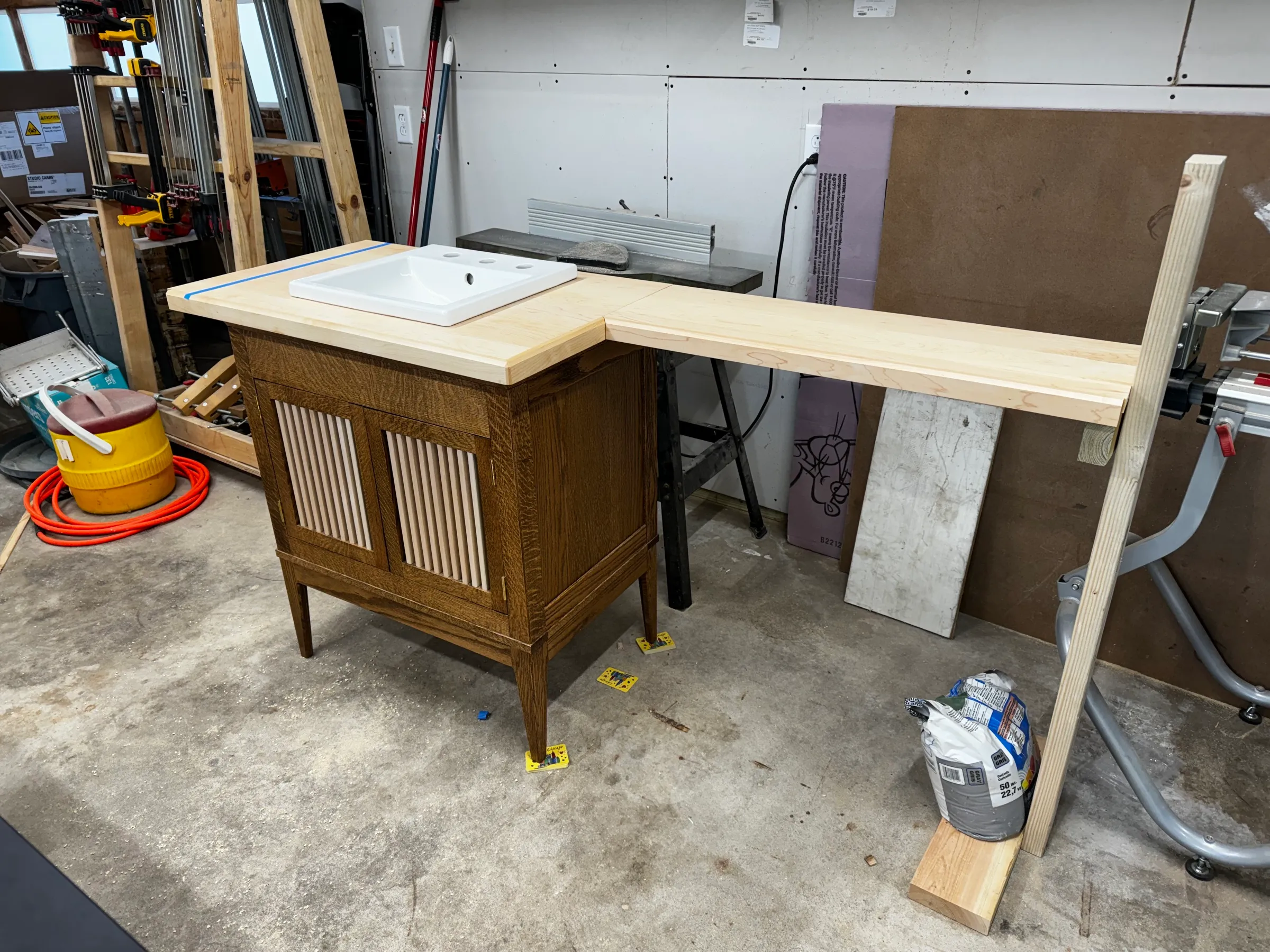 Finished vanity in the shop with the maple top and drop-in sink dry-fit and the corner shelf extension in place.