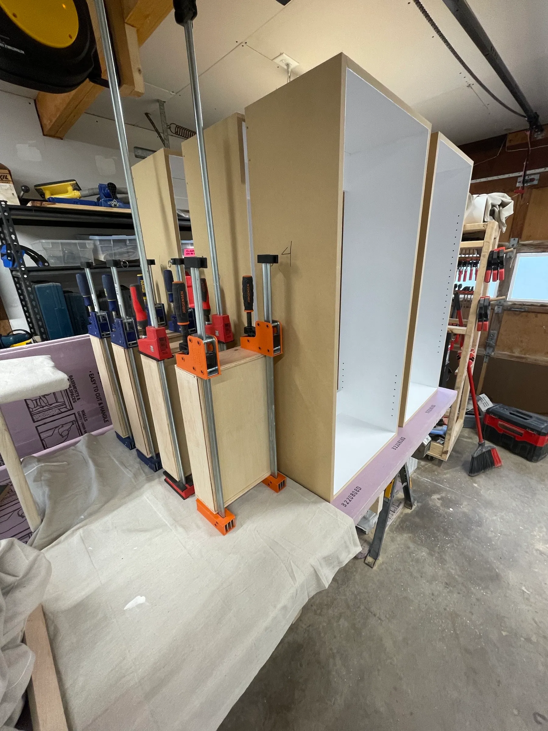 Cabinet carcasses clamped up with parallel clamps while the glue sets.