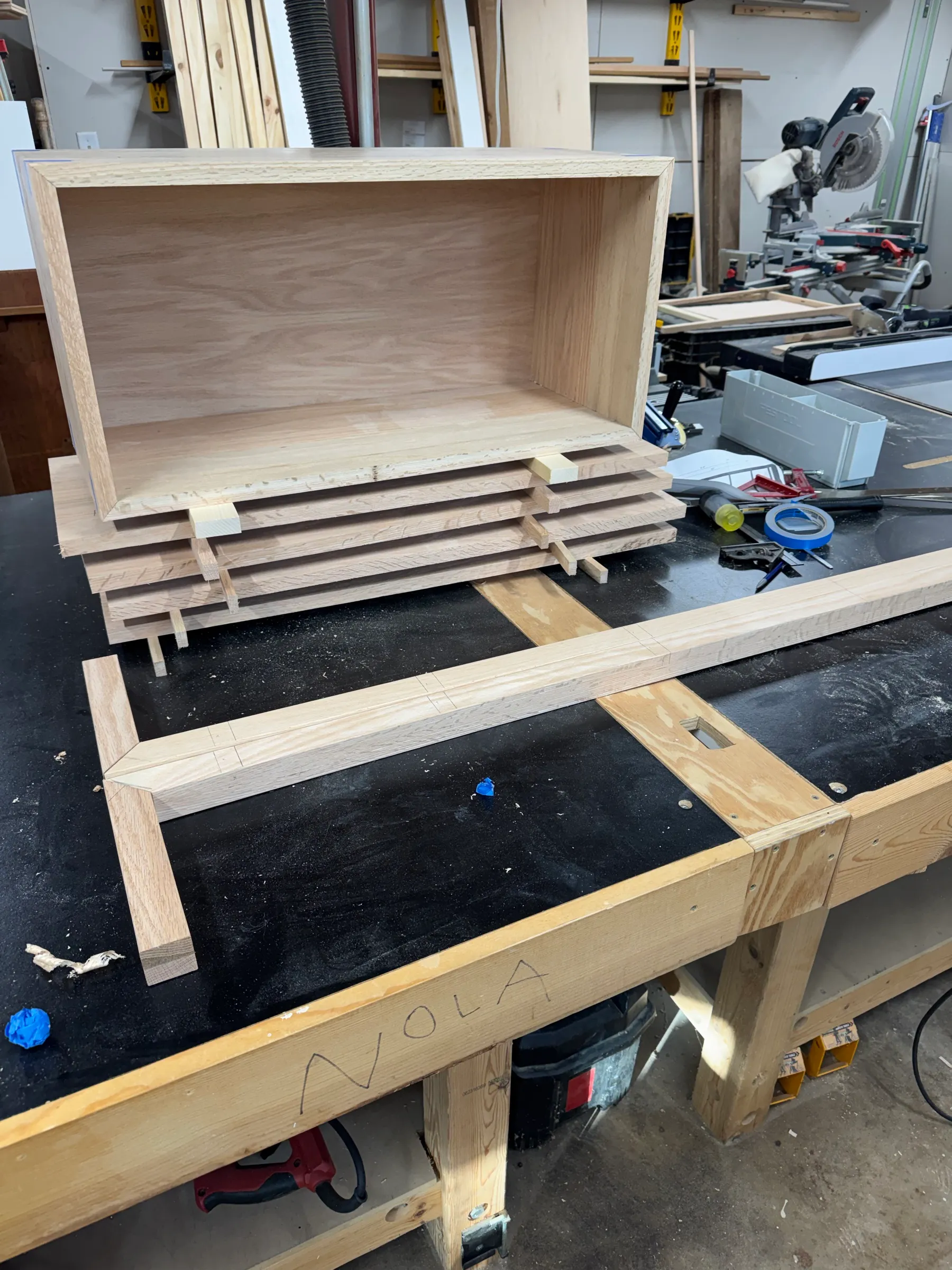 Dry-assembled red oak shelf parts and the open cabinet box laid out on the shop bench before finishing.