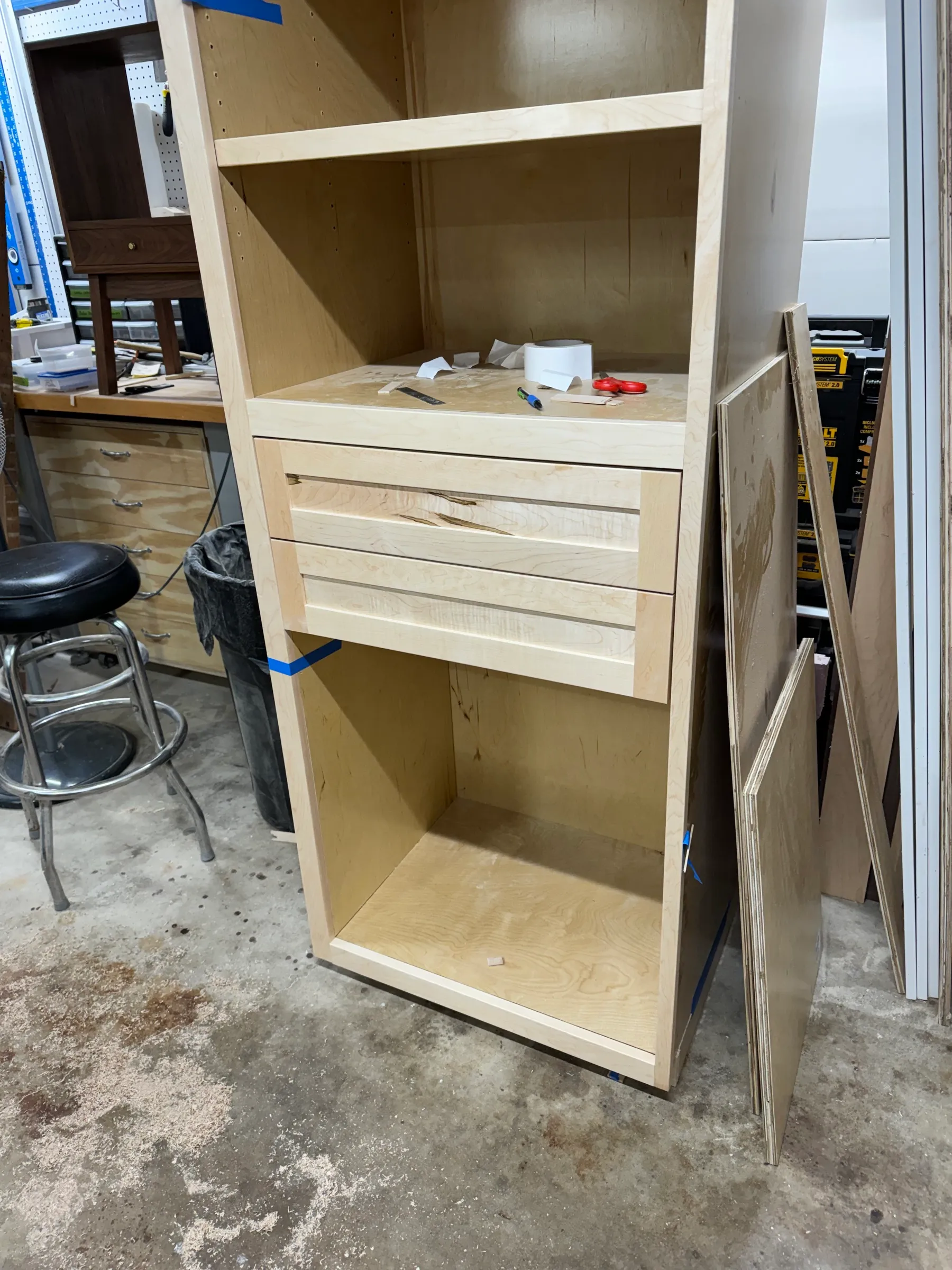 The lower cabinet section under construction, a reeded maple door fitted between open plywood bays.