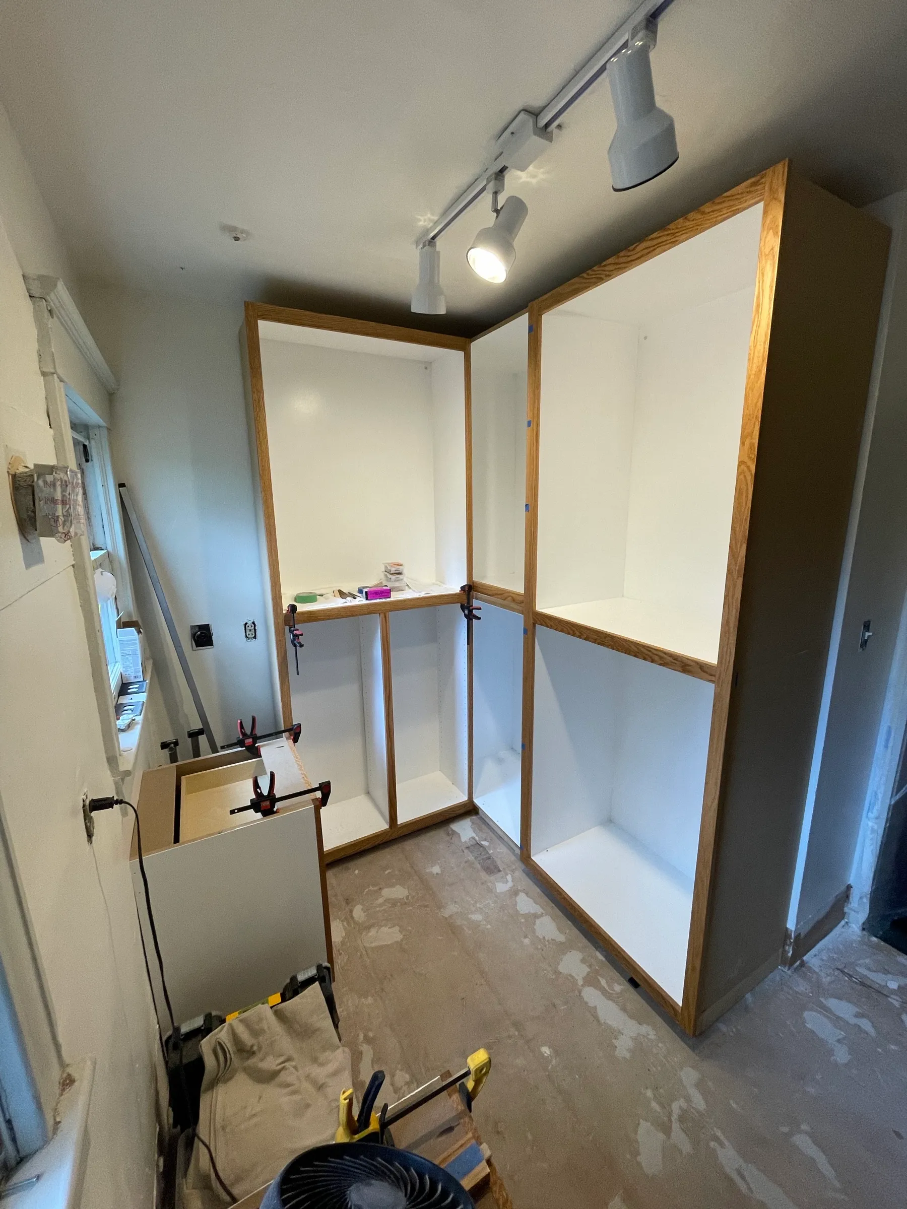 The cabinet boxes installed in the closet with oak face frames and white interiors, before the rods go in.