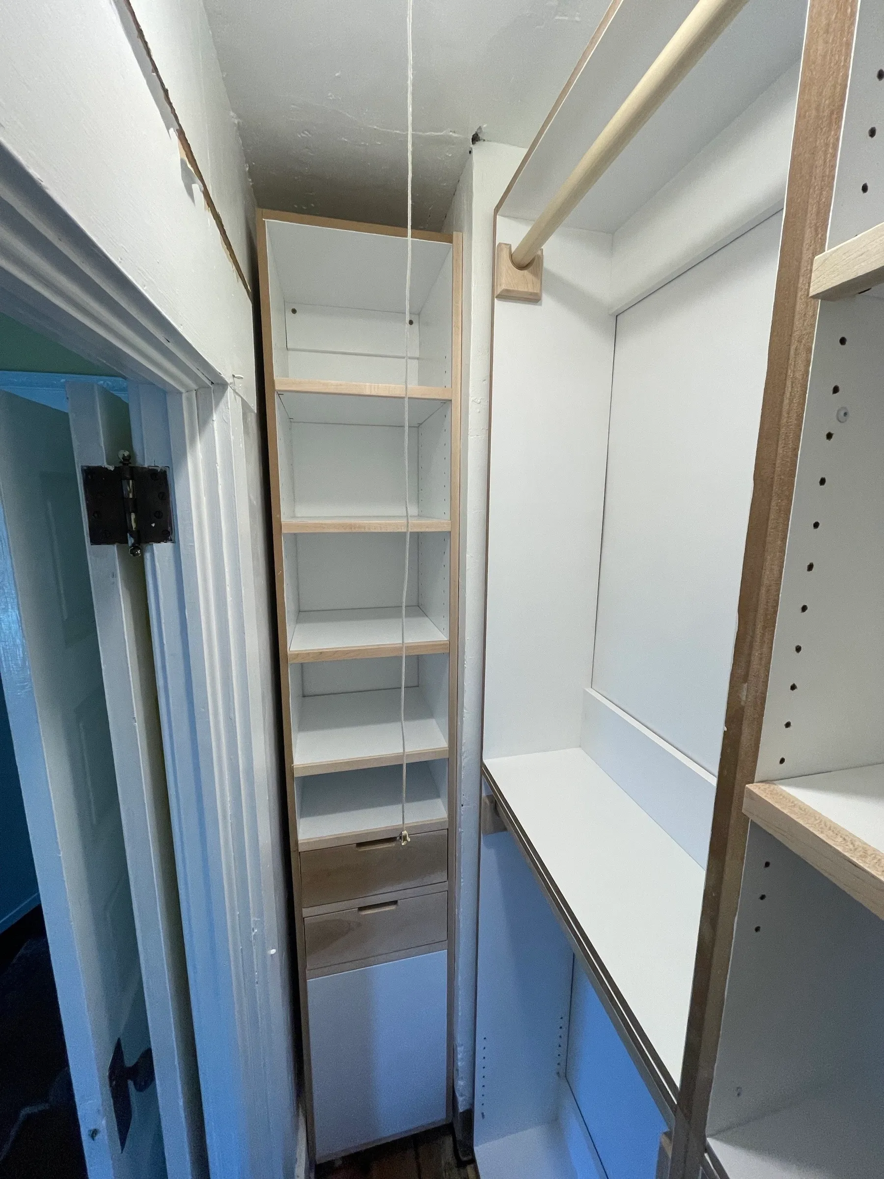 The closet during installation, shelf tower scribed to the wall beside a maple hanging rod and shelf.