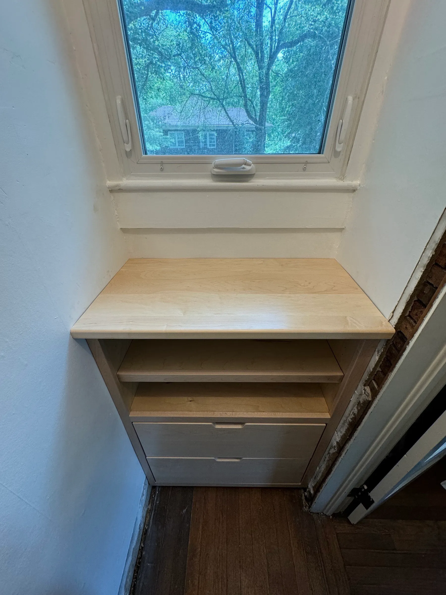 The maple counter installed under the closet window, with open shelves and two drawers below it.